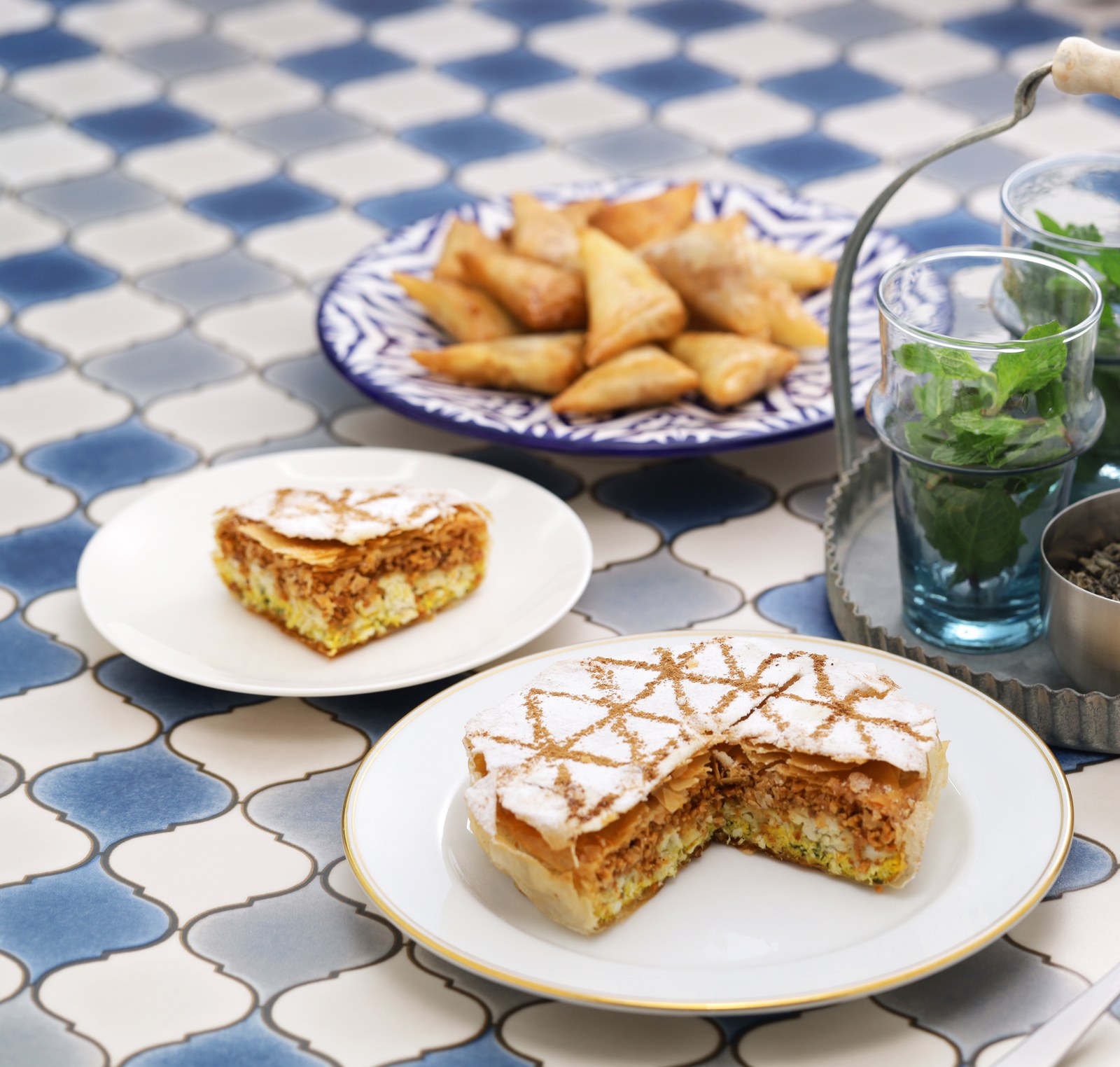 Pastilla dusted with cinnamon and icing sugar, briouats and Moroccan mint tea on zellige tile